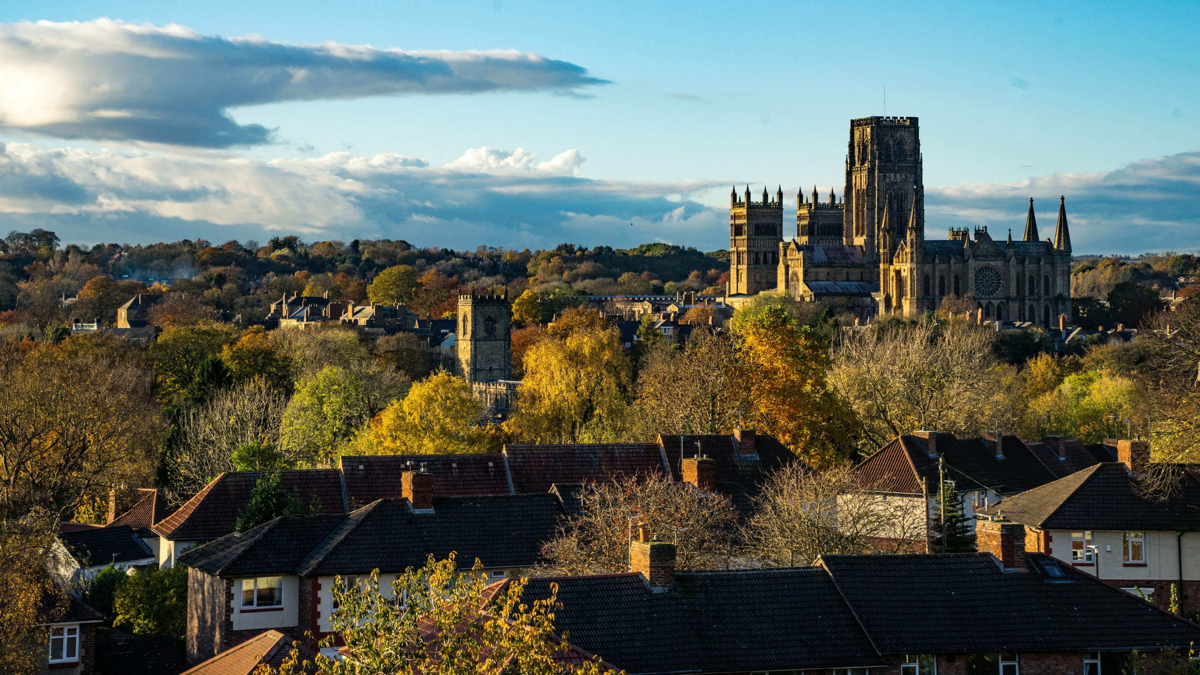 Durham Cathedral rising above autumn trees and the slate roofs of houses